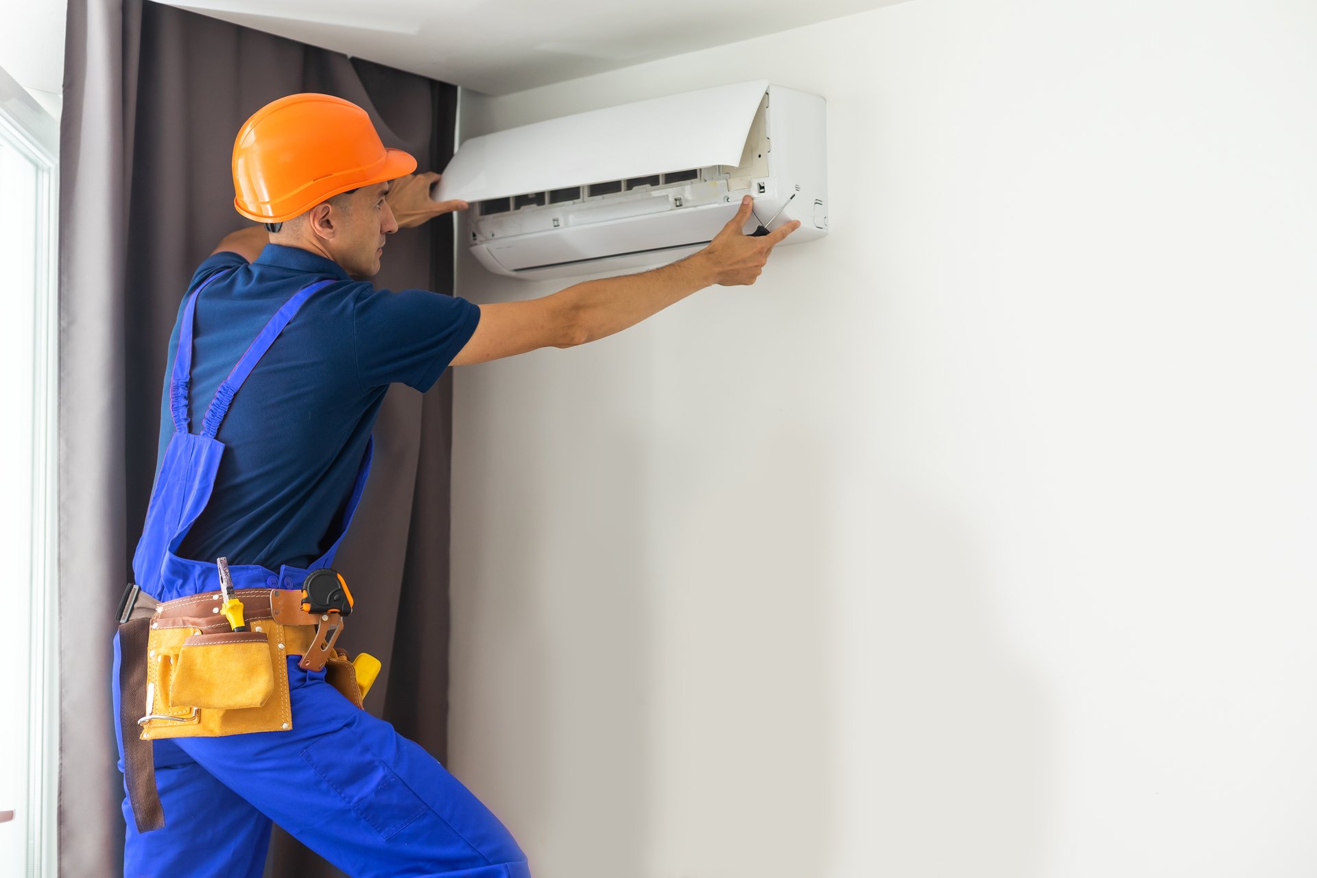 professional technician repairing ductless air conditioner.